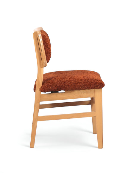 Opposite side view of the Vaya Home Mouton dining chair with orange boucle upholstery and a natural wood frame.