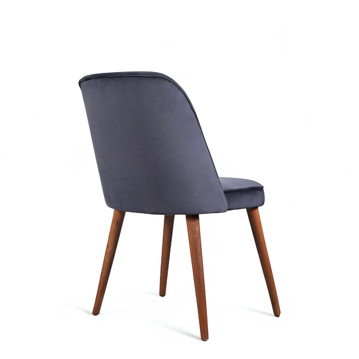 Rear angled view of the Vaya Home Netto dining chair featuring dark blue upholstery, a softly curved backrest, and tapered wood legs.