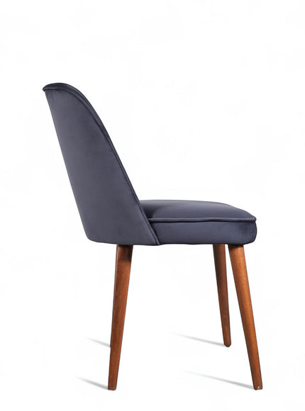 Side view of the Vaya Home Netto dining chair with dark blue upholstery, slim profile, and tapered wood legs.