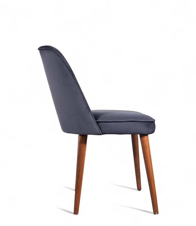 Side view of the Vaya Home Netto dining chair with dark blue upholstery, slim profile, and tapered wood legs.