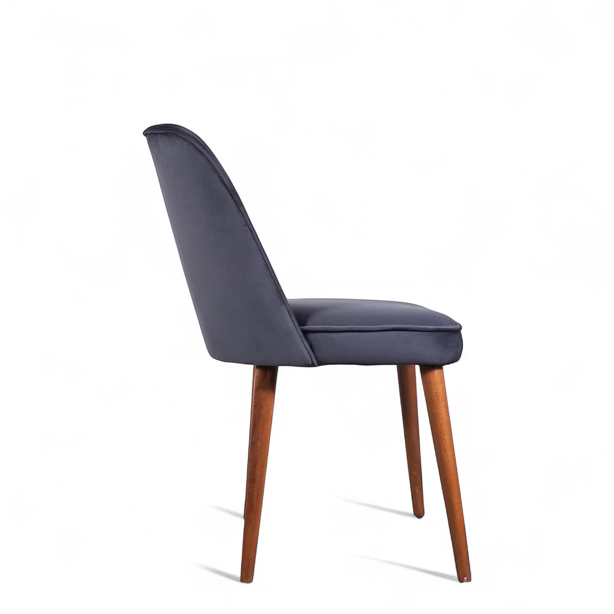 Side view of the Vaya Home Netto dining chair with dark blue upholstery, slim profile, and tapered wood legs.