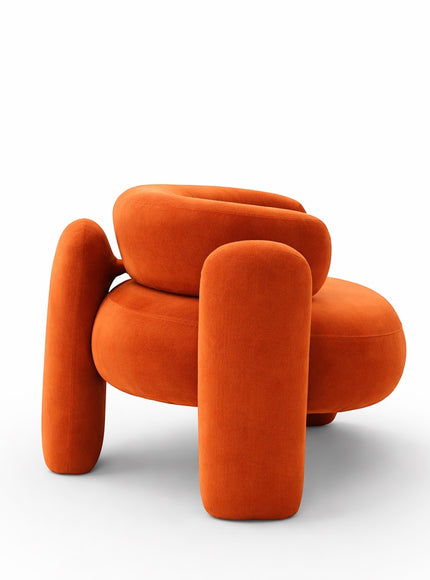 Side view of the Vaya Home Orbit accent chair featuring a sculptural silhouette, curved arms, and orange upholstery.