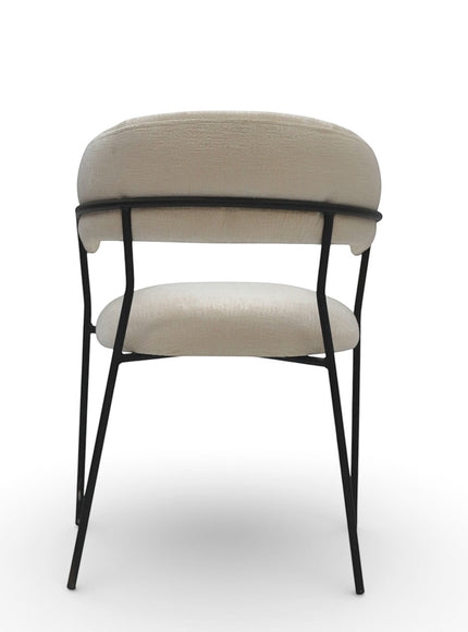 Back view of the Vaya Home Osso dining chair with cream upholstery, open back support detail, and black metal legs.