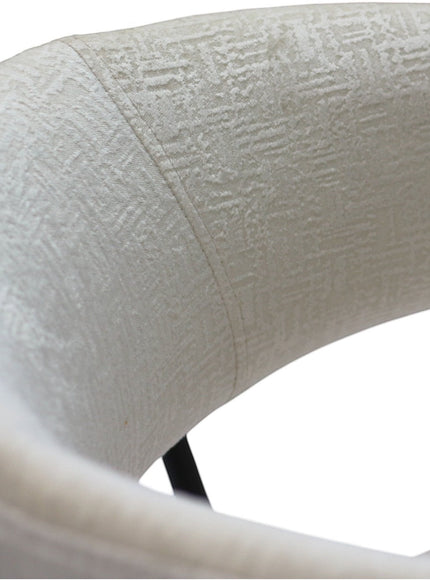 Close-up of the Vaya Home Osso dining chair showing cream textured upholstery and curved backrest detail.