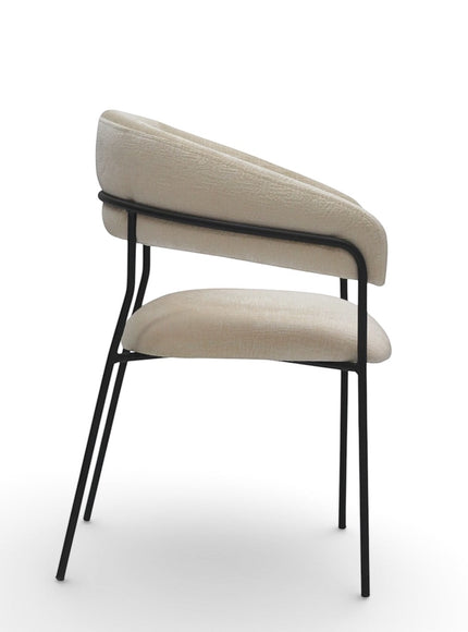 Side view of the Vaya Home Osso dining chair showing cream upholstery, a curved wraparound back, and black metal frame.