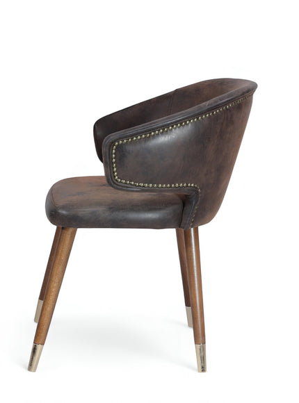 Opposite side view of the Vaya Home Pelle accent chair with dark brown leather-look upholstery, nailhead trim, and tapered wood legs with metal caps.