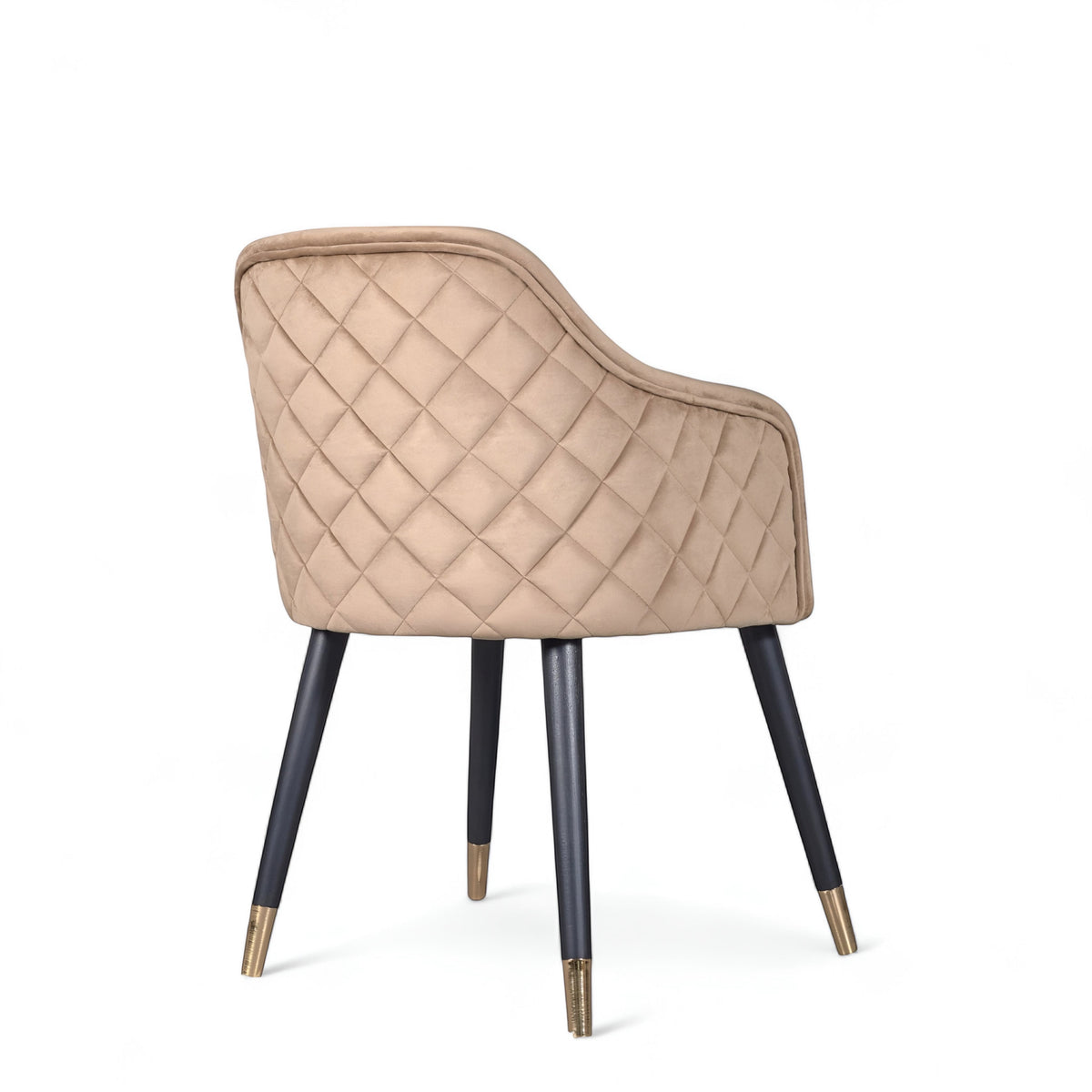 Rear angled view of the Vaya Home Pino dining chair featuring beige upholstery, diamond-quilted back detail, and black tapered legs with gold caps.
