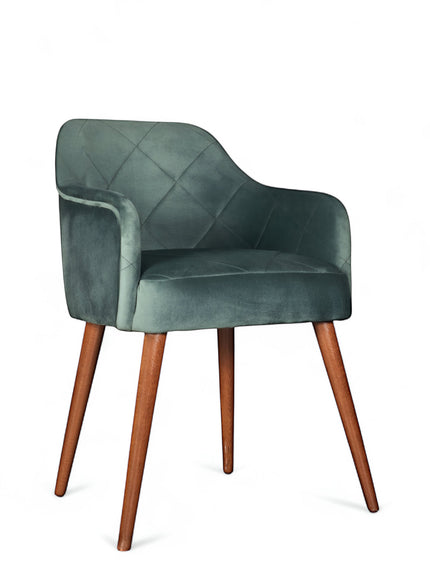 Front angled view of the Vaya Home Pino dining chair with green velvet upholstery, curved arms, and tapered wood legs.