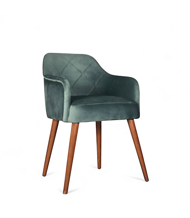 Front angled view of the Vaya Home Pino dining chair with green velvet upholstery, curved arms, and tapered wood legs.