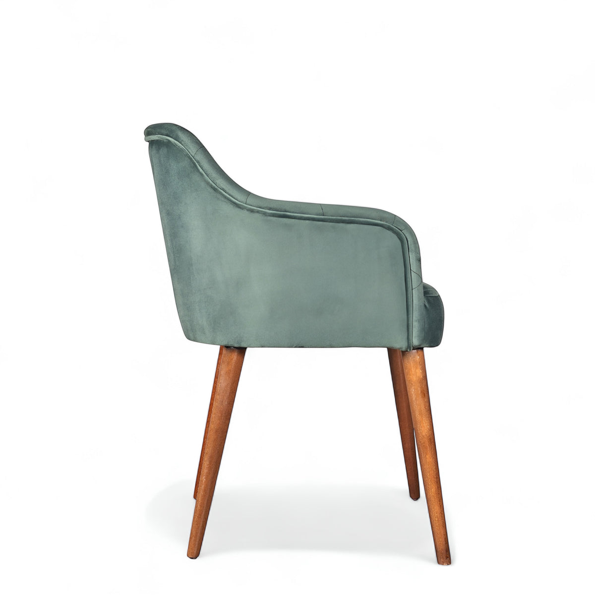 Side view of the Vaya Home Pino dining chair with green velvet upholstery, curved arm detail, and tapered wood legs.