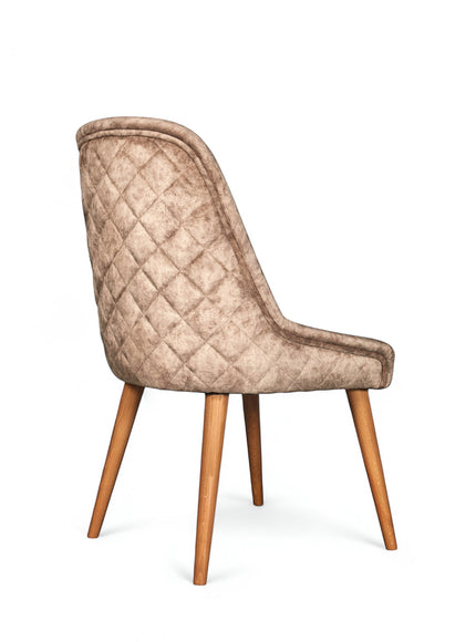 Rear angled view of the Vaya Home Reverie dining chair featuring beige leather velvet upholstery, diamond-quilted back detail, and tapered wood legs.