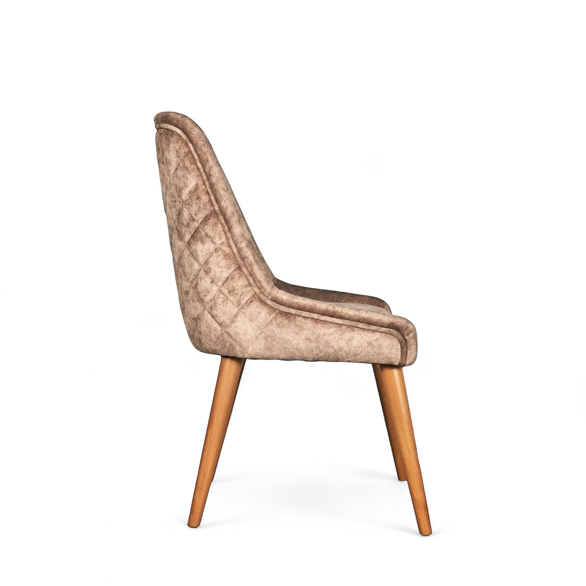 Side view of the Vaya Home Reverie dining chair in beige leather velvet upholstery with a slim profile and tapered wood legs.