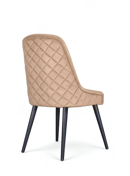 Rear angled view of the Vaya Home Reverie dining chair featuring beige upholstery, diamond-quilted back detail, and black tapered legs.