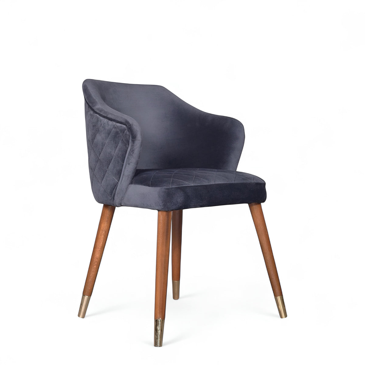 Front angled view of the Vaya Home Rioga dining chair with dark blue velvet upholstery, curved armrests, and tapered wood legs with gold caps.