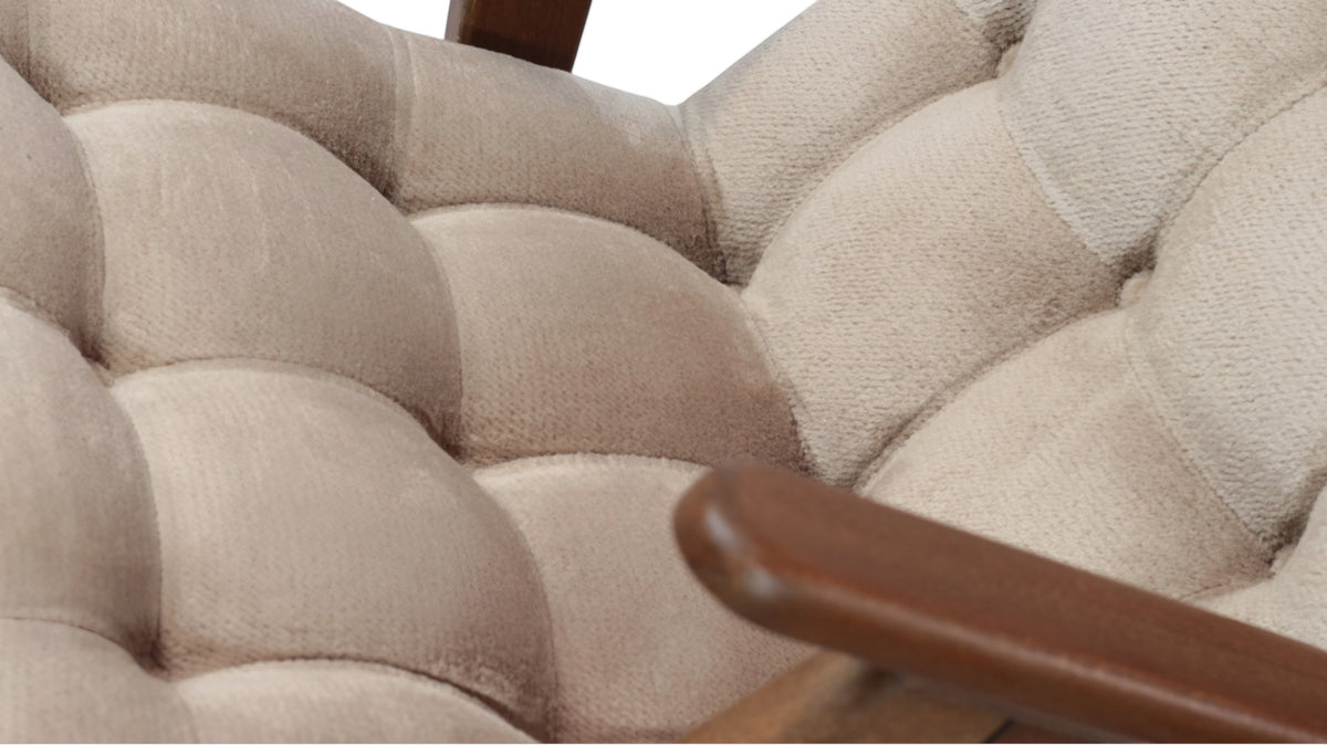 Close-up of the Vaya Home Riposo accent chair showing beige tufted upholstery and wood arm detail.