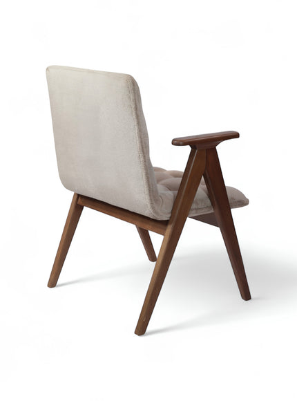 Rear angled view of the Vaya Home Riposo accent chair with beige upholstery, sculpted wood arms, and angled wood legs.