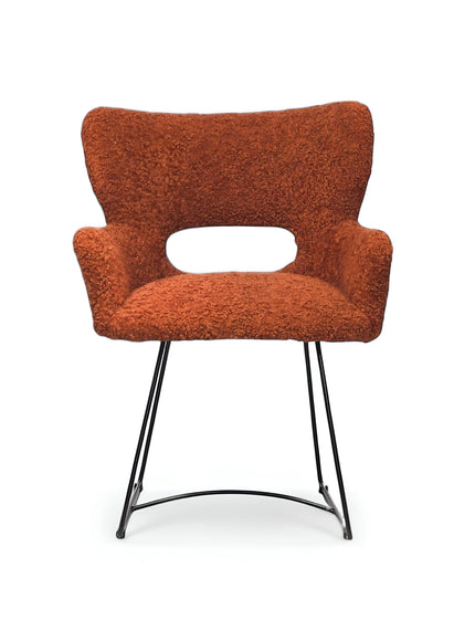 Front view of the Vaya Home Rolf accent chair featuring orange boucle upholstery, an open back cutout, and a black metal sled base.