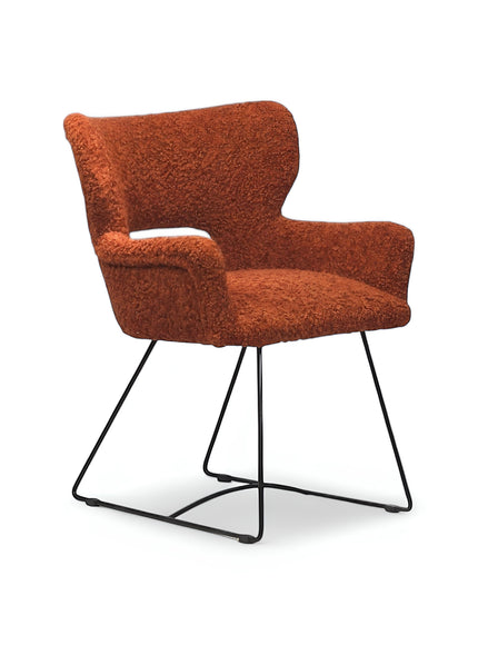 Product view of the Vaya Home Rolf accent chair in orange boucle upholstery with sculpted arms and a black metal sled base.