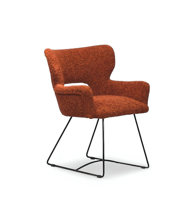 Product view of the Vaya Home Rolf accent chair in orange boucle upholstery with sculpted arms and a black metal sled base.