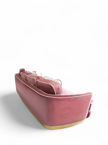 Back view of the Vaya Home Rose curved sofa with a rounded silhouette, pink velvet upholstery, and gold base trim.