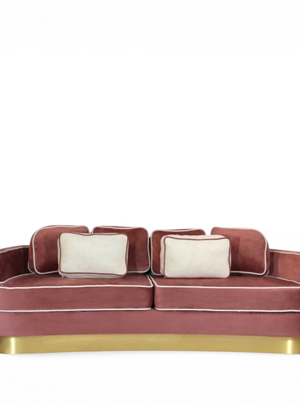 Front view of the Vaya Home Rose curved sofa with pink velvet upholstery, accent cushions, contrast piping, and a gold base.
