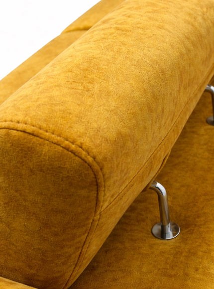 Close-up of the Vaya Home Saffron sofa showing mustard yellow upholstery, rounded armrest stitching, and metal leg detail.