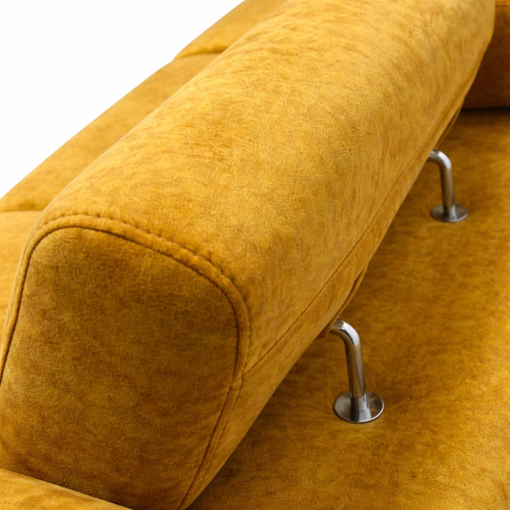 Close-up of the Vaya Home Saffron sofa showing mustard yellow upholstery, rounded armrest stitching, and metal leg detail.