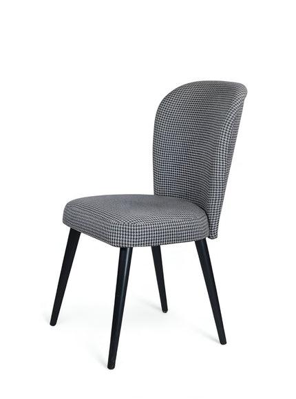 Front angled view of the Vaya Home Scacchi dining chair featuring black and white houndstooth upholstery and black tapered legs.