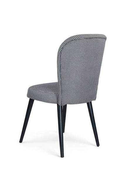 Rear angled view of the Vaya Home Scacchi dining chair featuring houndstooth upholstery and black tapered legs.