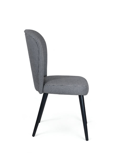 Side rear view of the Vaya Home Scacchi dining chair with houndstooth upholstery, curved backrest, and black tapered legs.