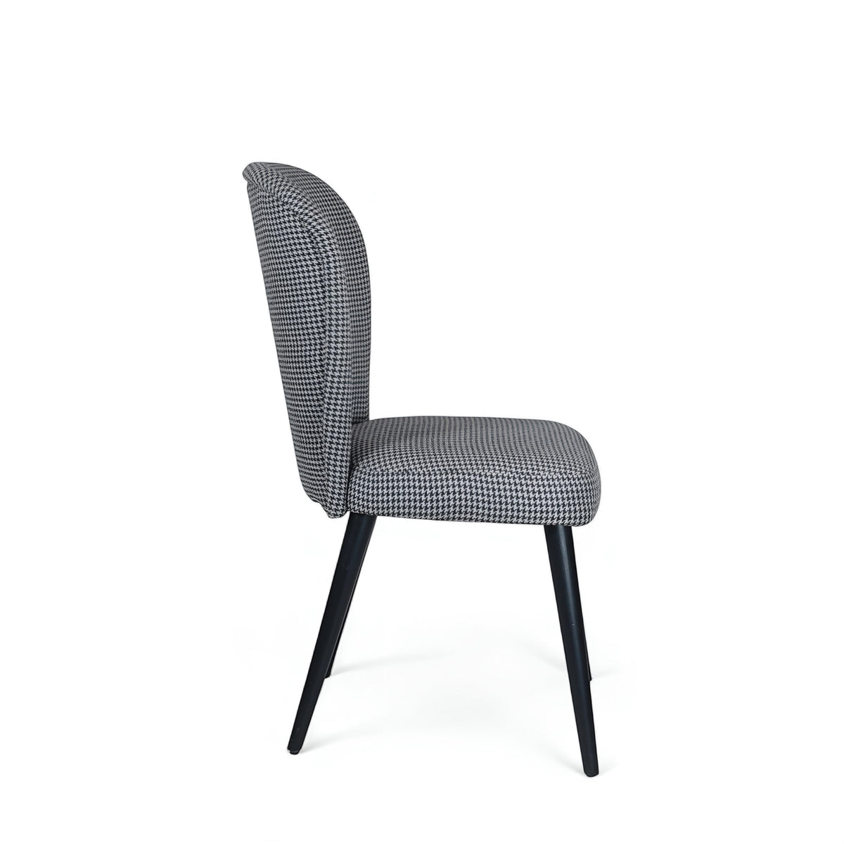 Side rear view of the Vaya Home Scacchi dining chair with houndstooth upholstery, curved backrest, and black tapered legs.