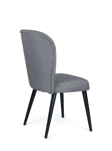 Side view of the Vaya Home Scacchi dining chair with black and white houndstooth upholstery and black tapered legs.