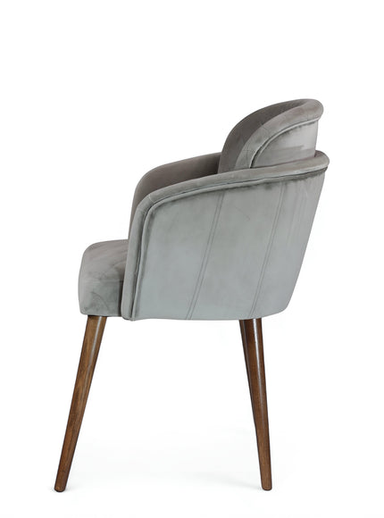 Side view of the Vaya Home Silver dining chair featuring gray upholstery, curved arms, and tapered wood legs.