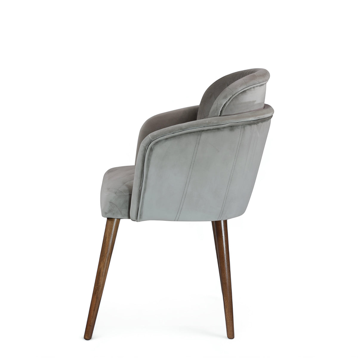 Side view of the Vaya Home Silver dining chair featuring gray upholstery, curved arms, and tapered wood legs.