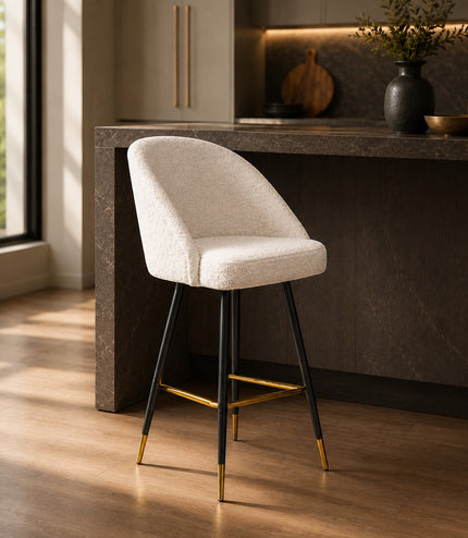 Vaya Home Sloan bar stool with white upholstery, black metal legs, and gold footrest detailing, styled at a modern kitchen island.
