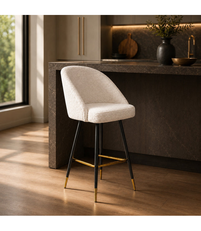 Vaya Home Sloan bar stool with white upholstery, black metal legs, and gold footrest detailing, styled at a modern kitchen island.