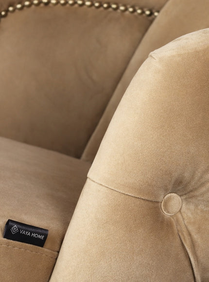 Close-up of the Vaya Home Sorelle dining chair showing beige velvet upholstery, button tufting, and curved arm detail.