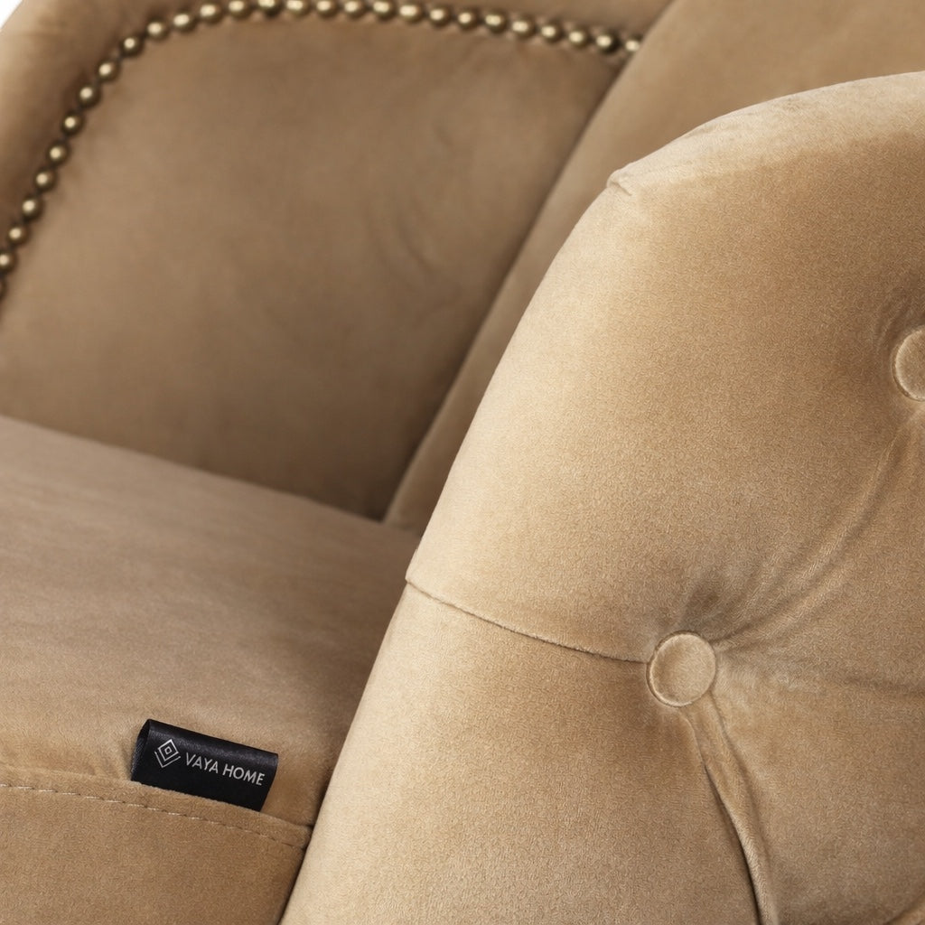 Close-up of the Vaya Home Sorelle dining chair showing beige velvet upholstery, button tufting, and curved arm detail.