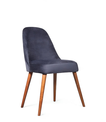 Front angled view of the Vaya Home Stretto dining chair with dark blue velvet upholstery and tapered wood legs.