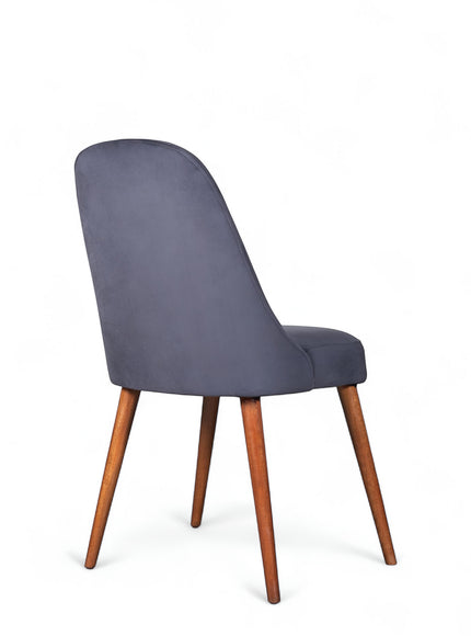 Rear angled view of the Vaya Home Stretto dining chair featuring dark blue velvet upholstery and tapered wood legs.