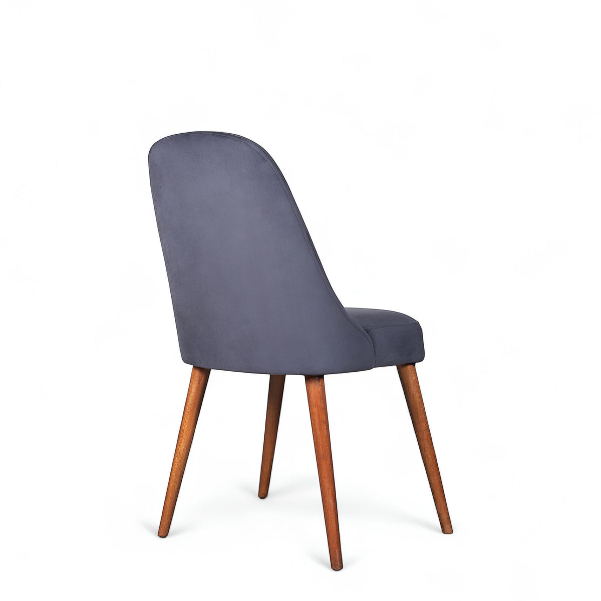 Rear angled view of the Vaya Home Stretto dining chair featuring dark blue velvet upholstery and tapered wood legs.