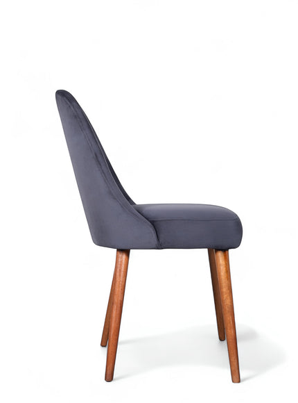 Side view of the Vaya Home Stretto dining chair with dark blue velvet upholstery and tapered wood legs.