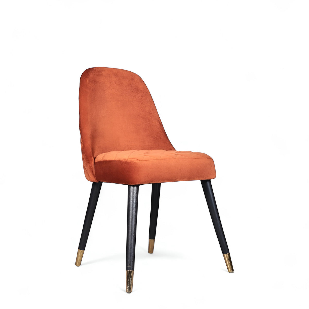 Front angled view of the Vaya Home Stretto dining chair with orange velvet upholstery, slim profile, and black tapered legs with gold caps.