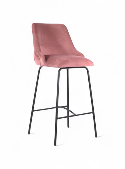 Front angled view of the Vaya Home Toffel bar stool with pink velvet upholstery, tufted backrest, and black metal legs.