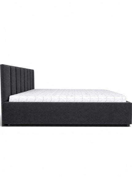 Side view of the Vaya Home Torino bed featuring dark gray upholstery, a channel-tufted headboard, and a low platform frame.