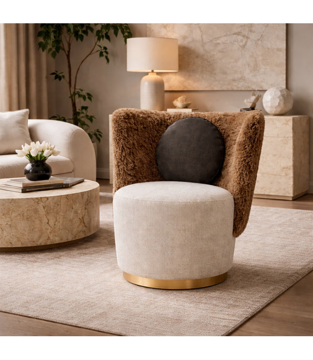 Vaya Home Valmont accent chair with a cream upholstered seat, brown textured wraparound back, gold base detail, and black round cushion, styled in a modern interior.
