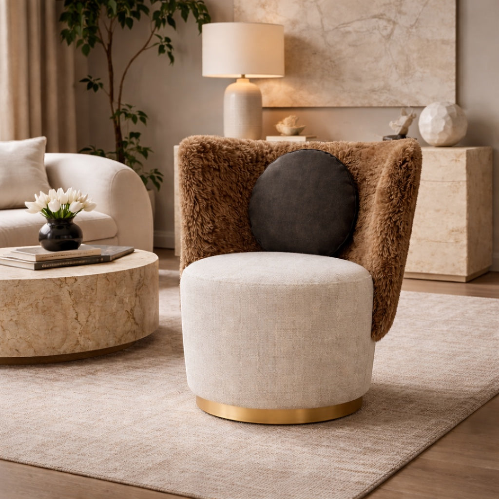 Vaya Home Valmont accent chair with a cream upholstered seat, brown textured wraparound back, gold base detail, and black round cushion, styled in a modern interior.