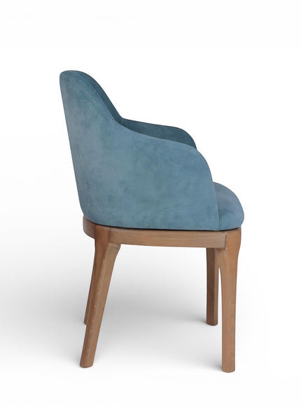 Side view of the Vaya Home Verve dining chair with blue upholstery, curved arms, and tapered wood legs.