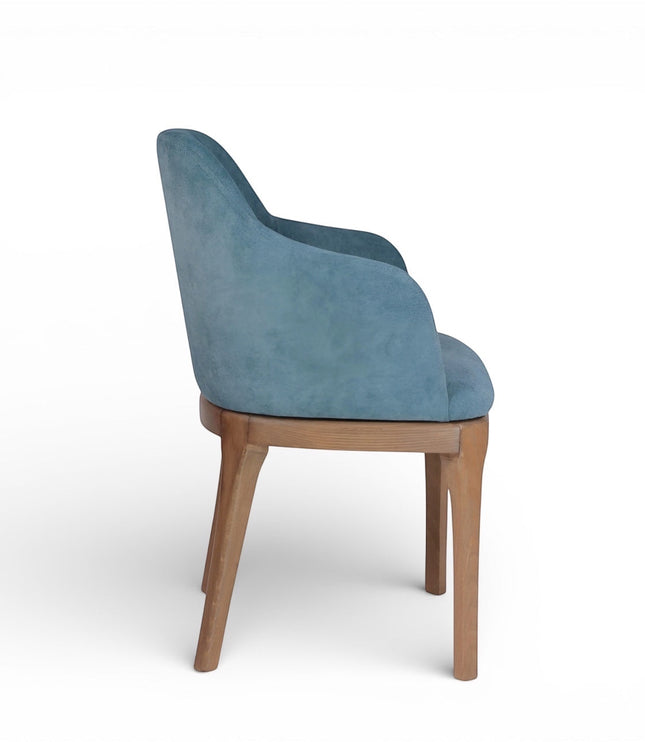 Side view of the Vaya Home Verve dining chair with blue upholstery, curved arms, and tapered wood legs.